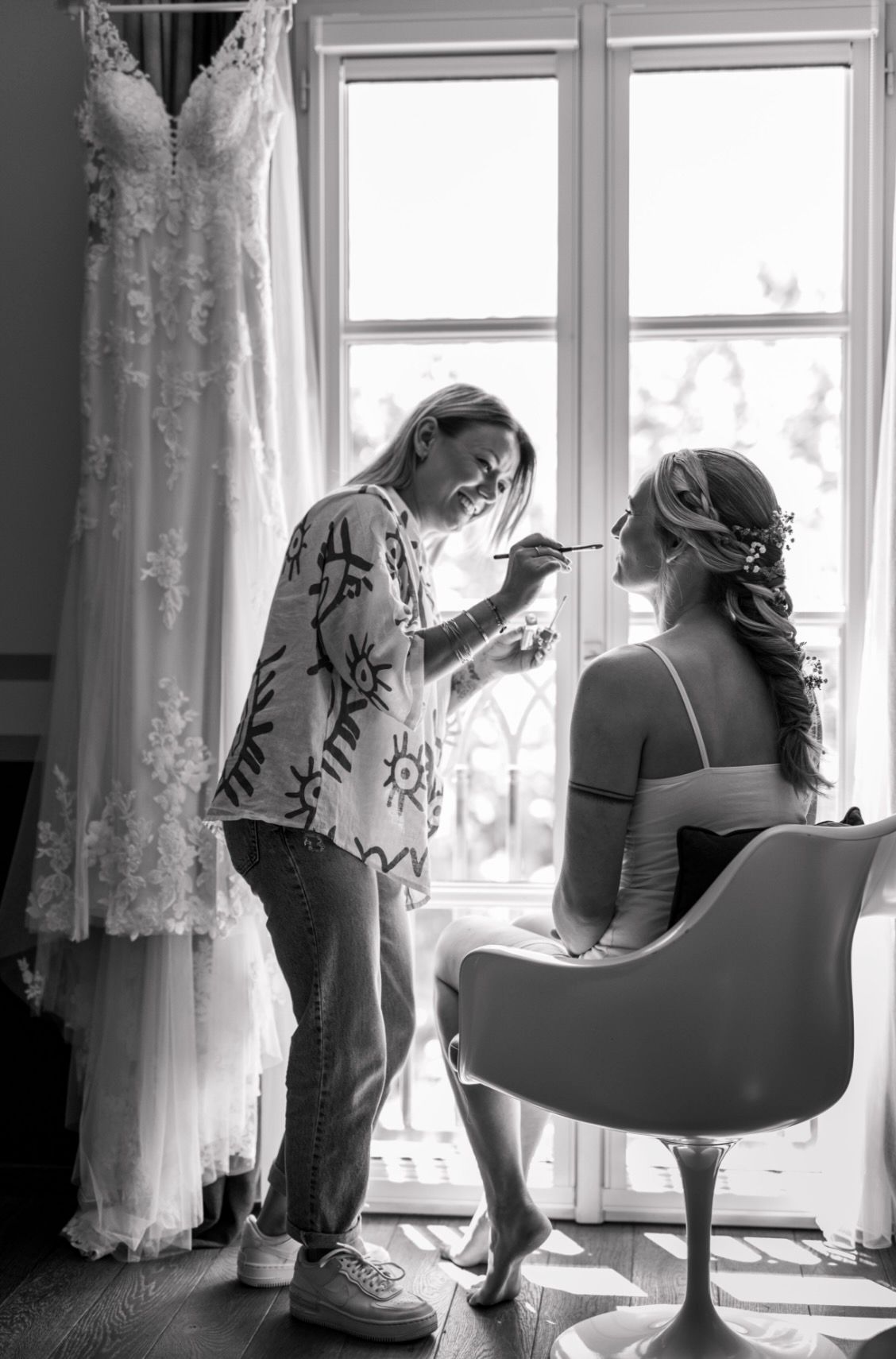 A black and white photo series shows intimate moments of a bride getting ready on her wedding day near a window.