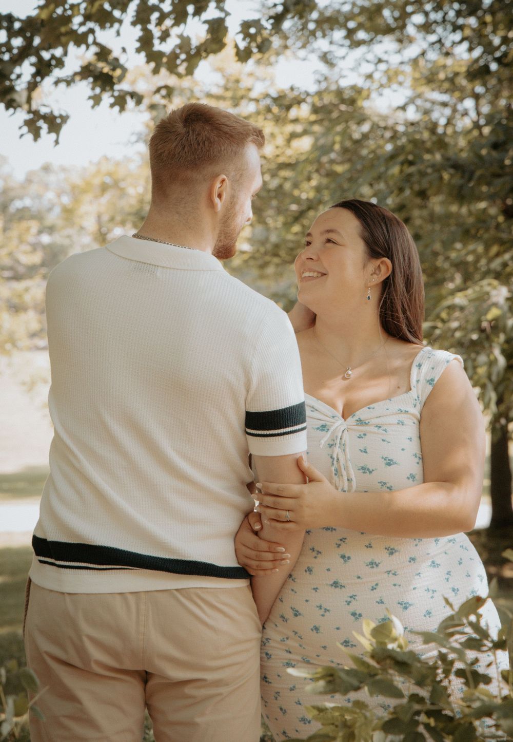 A tender moment between a couple in a garden setting, with soft sunlight filtering through the trees.