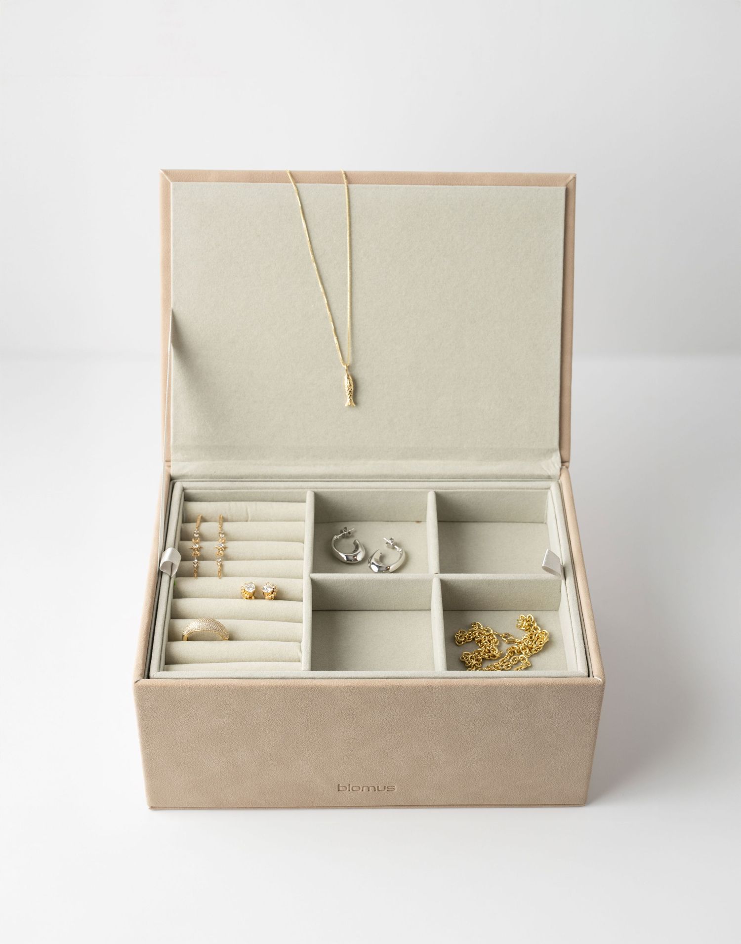 Open beige jewelry box with compartments displaying rings and necklaces against white background.