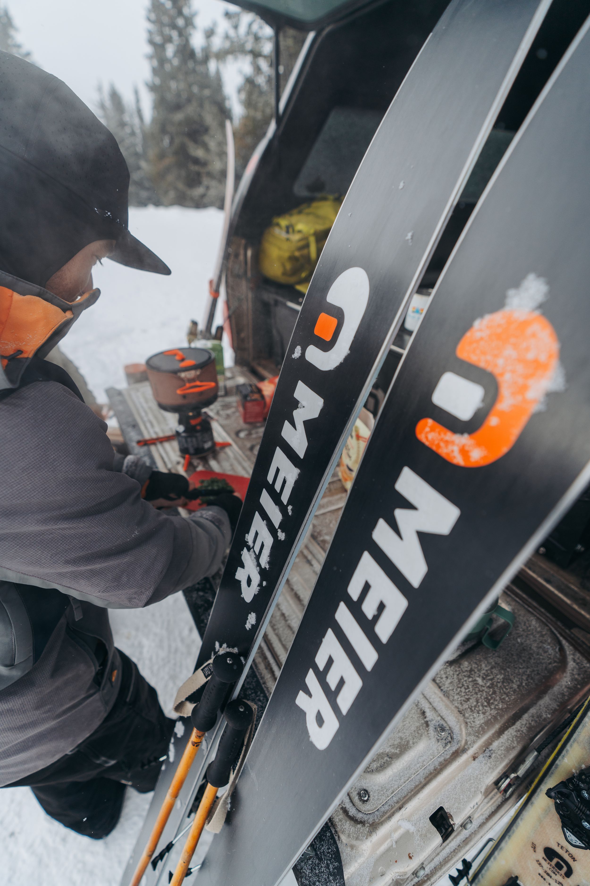 Close-up shots of black ski equipment showing detailed views of bindings and gear against snowy background.
