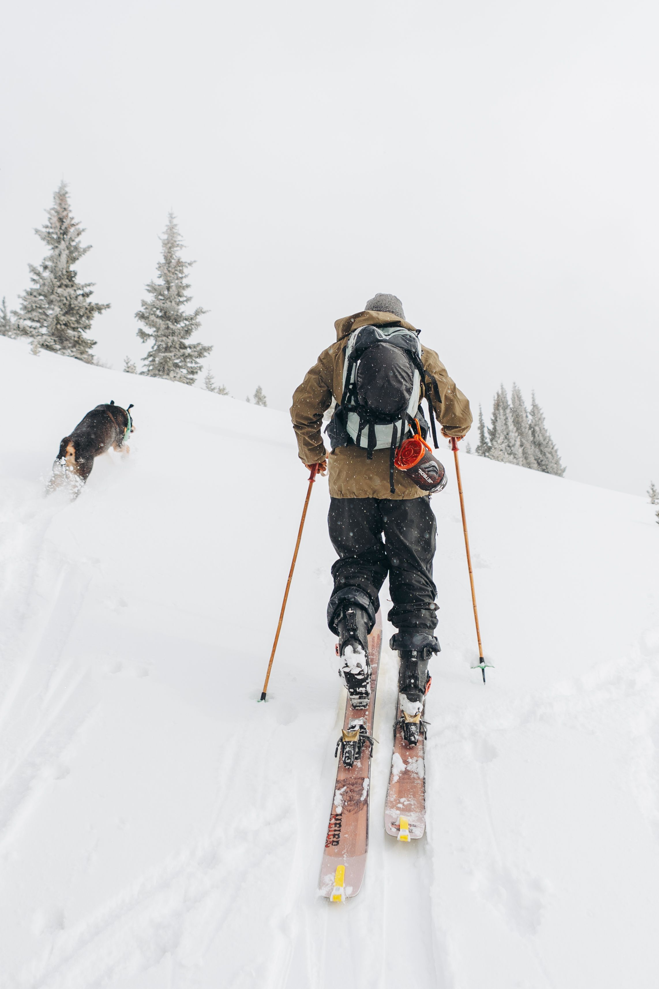 A sequence of four photos showing a backcountry skier ascending a snowy mountain slope in winter conditions.
