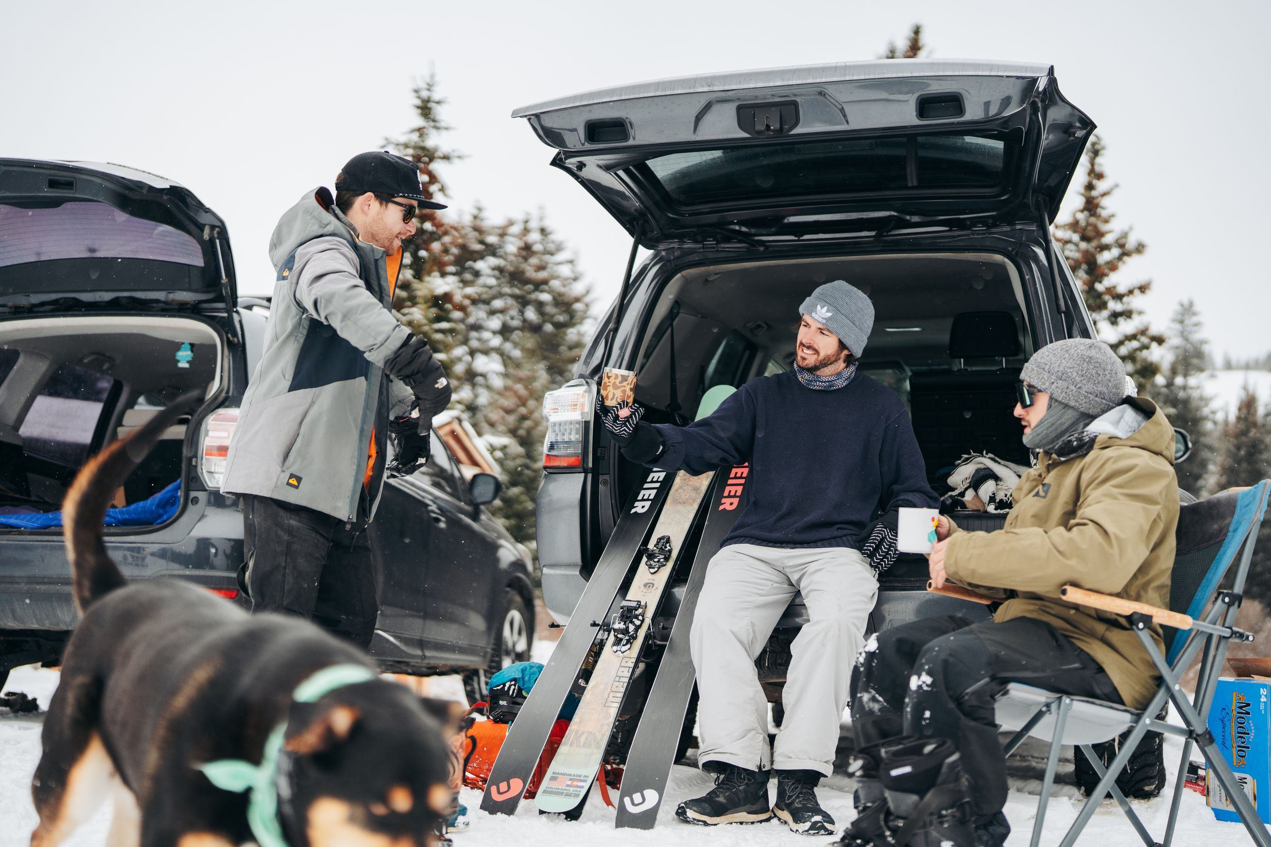 Group of friends loading camping gear and luggage into the back of an SUV on a winter day.