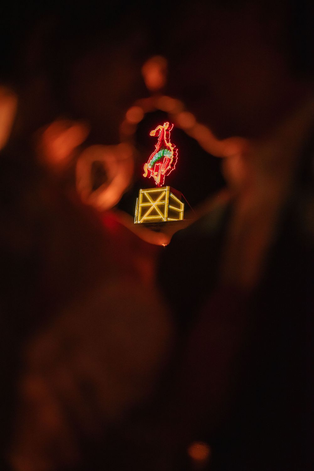 Neon signs and fire elements create an atmospheric display of red and orange lights in the dark.