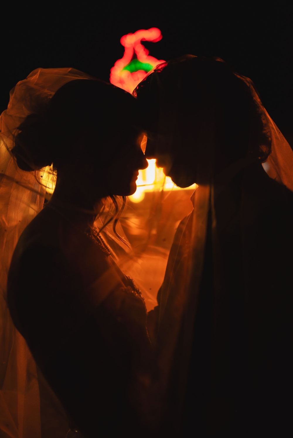 Silhouettes of people with cowboy hats dancing in a dimly lit space illuminated by warm orange lighting.