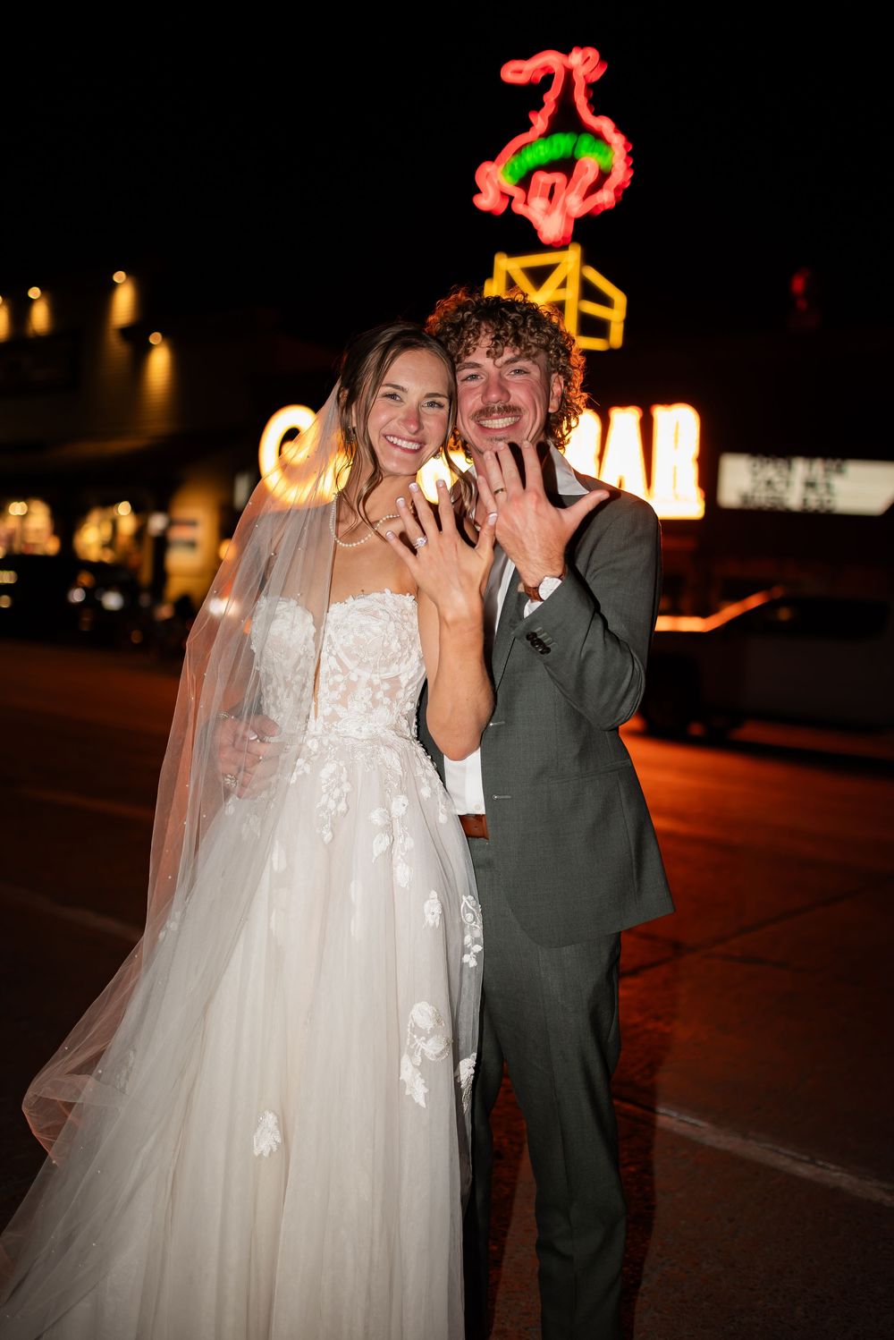 A bride and groom share a joyful moment together during their nighttime wedding celebration.