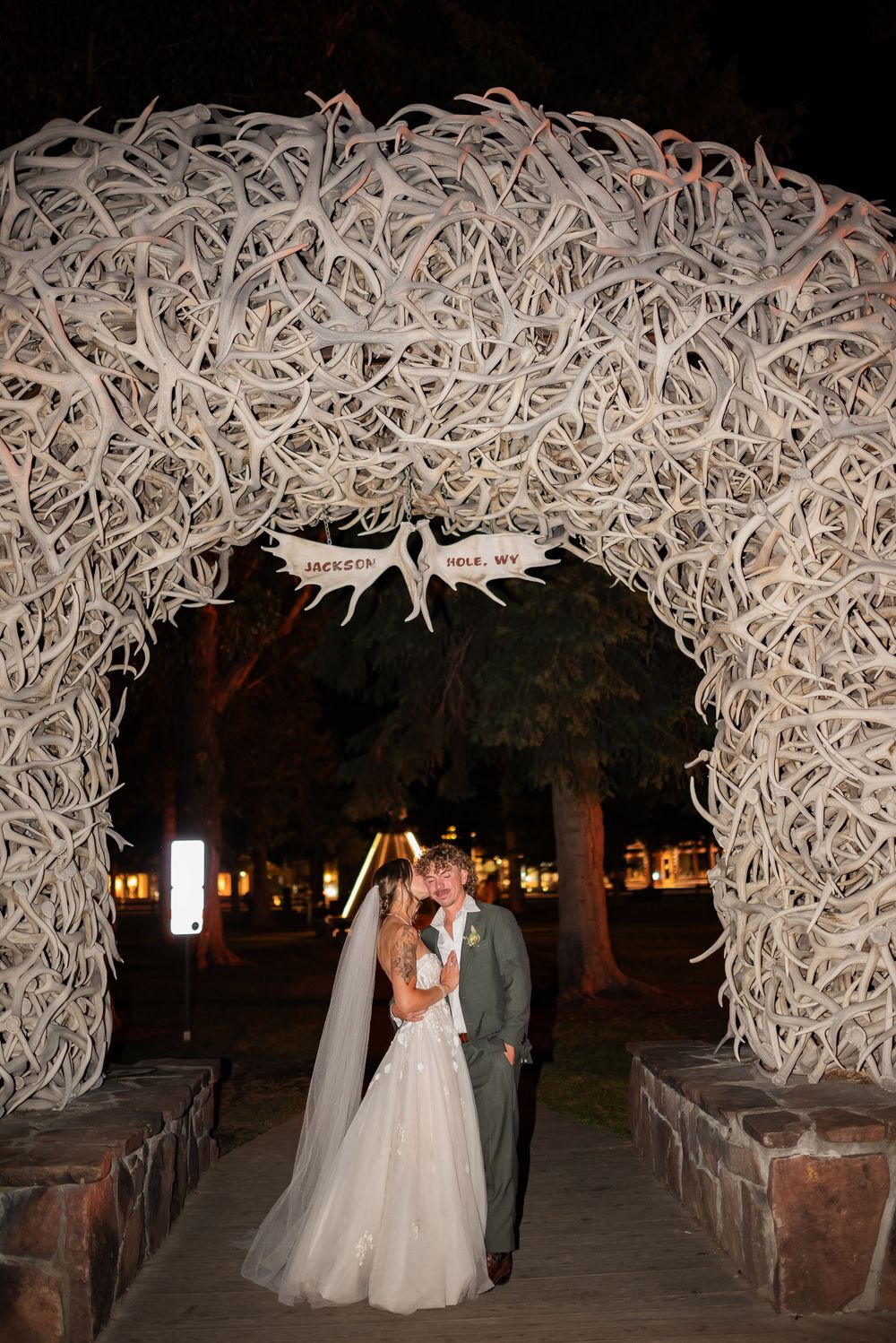 A romantic wedding walkway illuminated at night under a stunning arch made of white antler-like decorations.