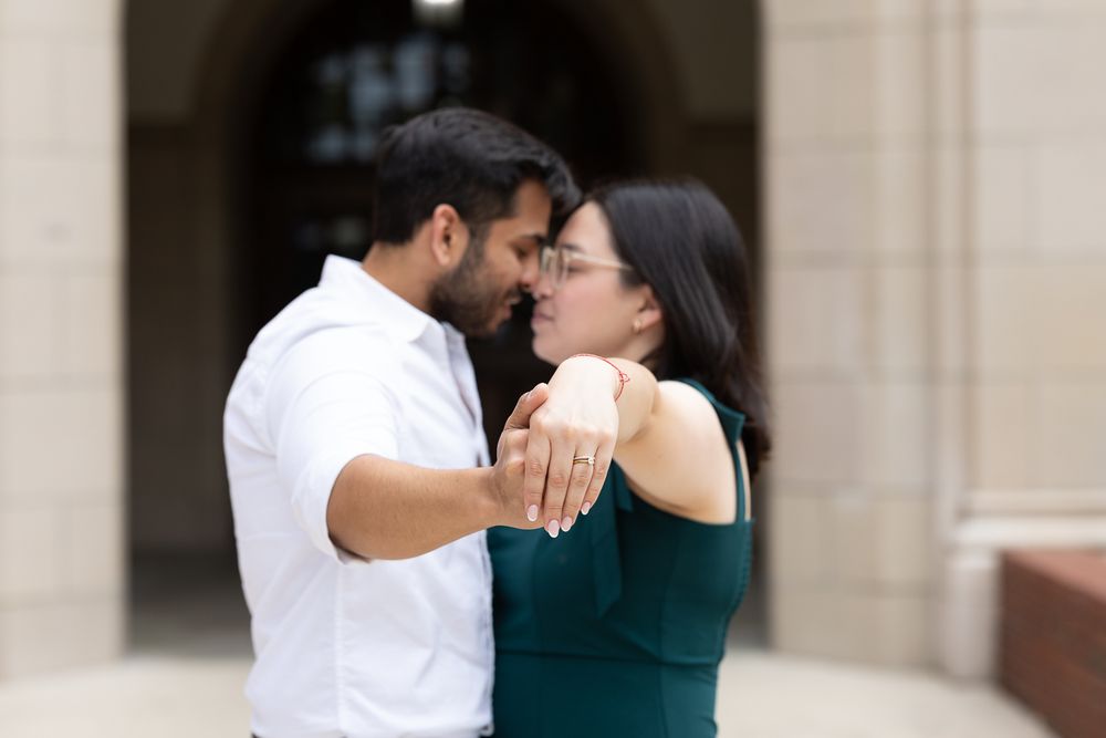 A romantic couple in white and green outfits share an intimate moment in front of a stone building.