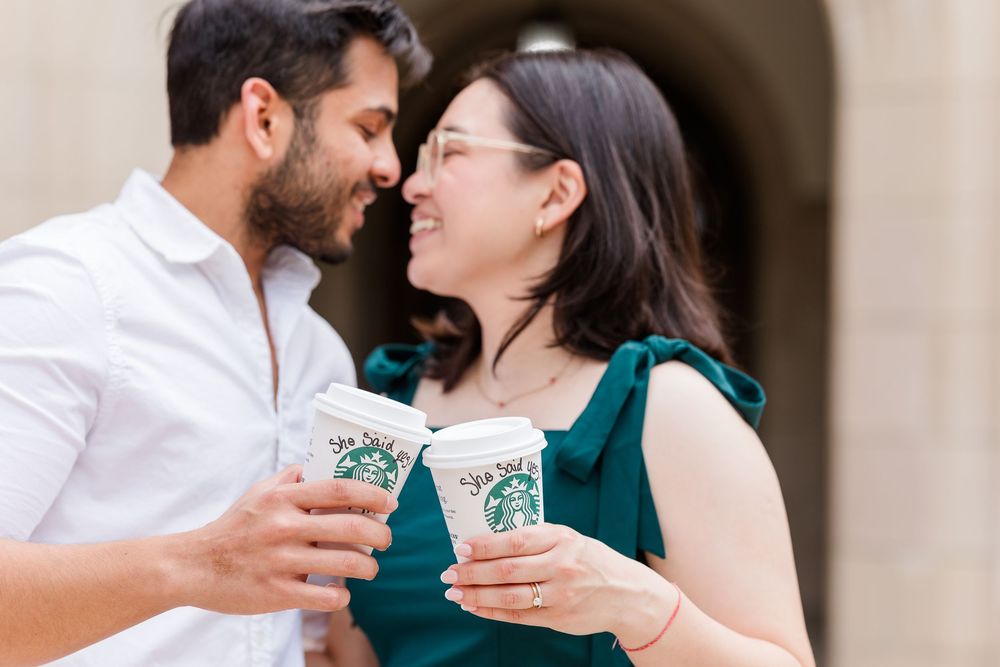 A couple shares a romantic moment while holding Starbucks drinks together.