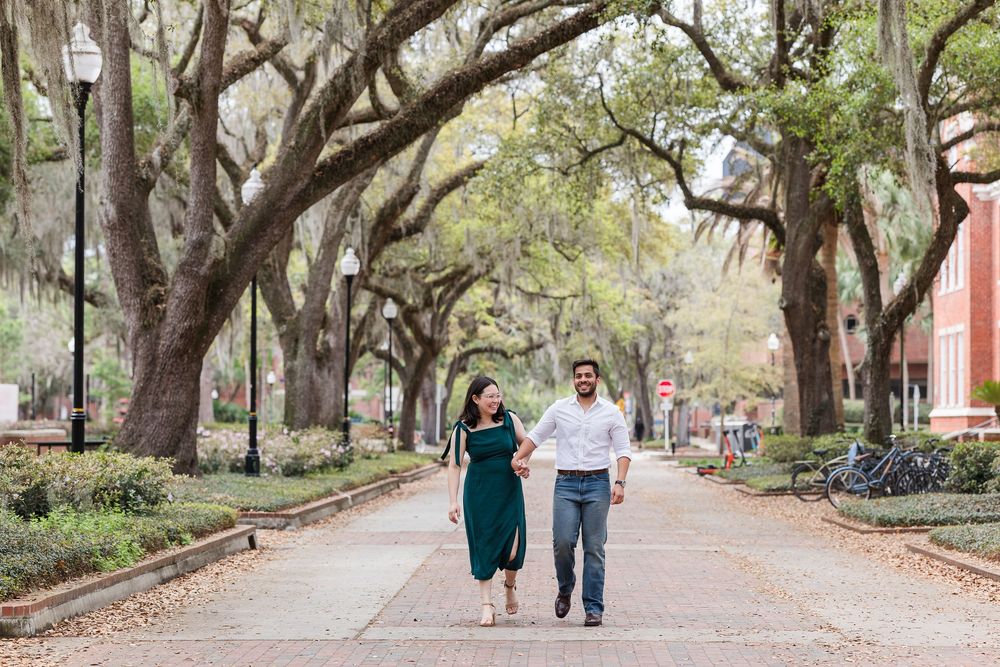 A couple walks together on a tree-lined path in a scenic park setting.