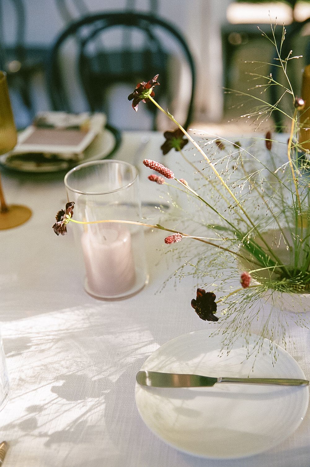Elegant table setting with delicate glassware and wispy floral arrangements casting soft shadows.