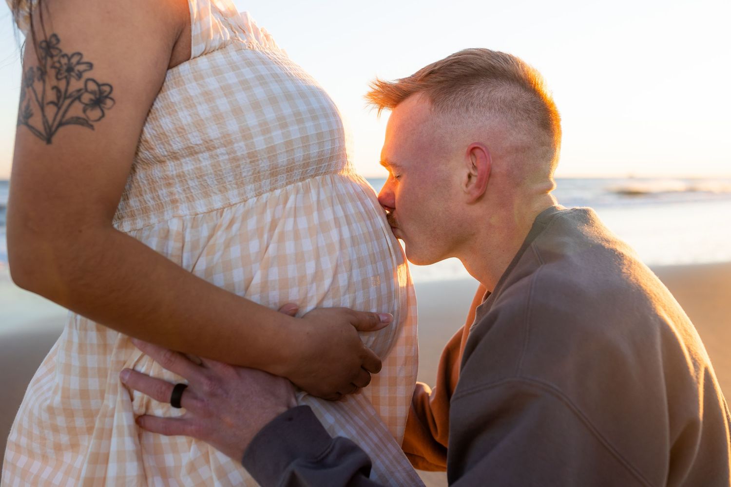 Expecting mother wearing a soft neutral flowing dress during a beach maternity session at sunset in Emerald Isle, North Carolina