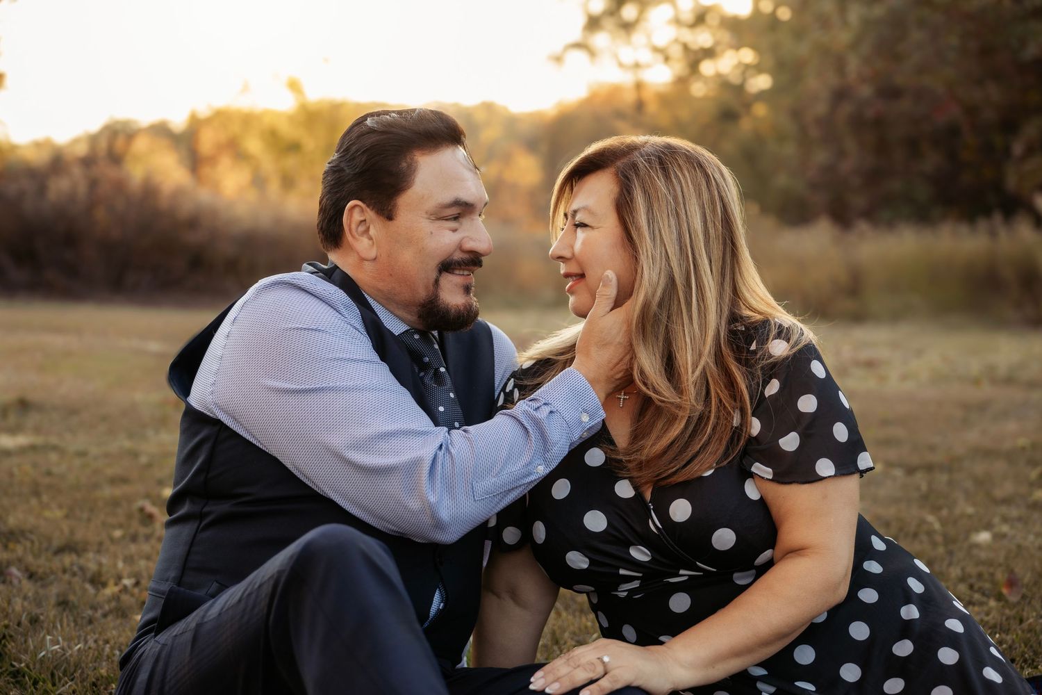 Happy mature couple sitting in golden field laughing and enjoying a romantic outdoor moment.