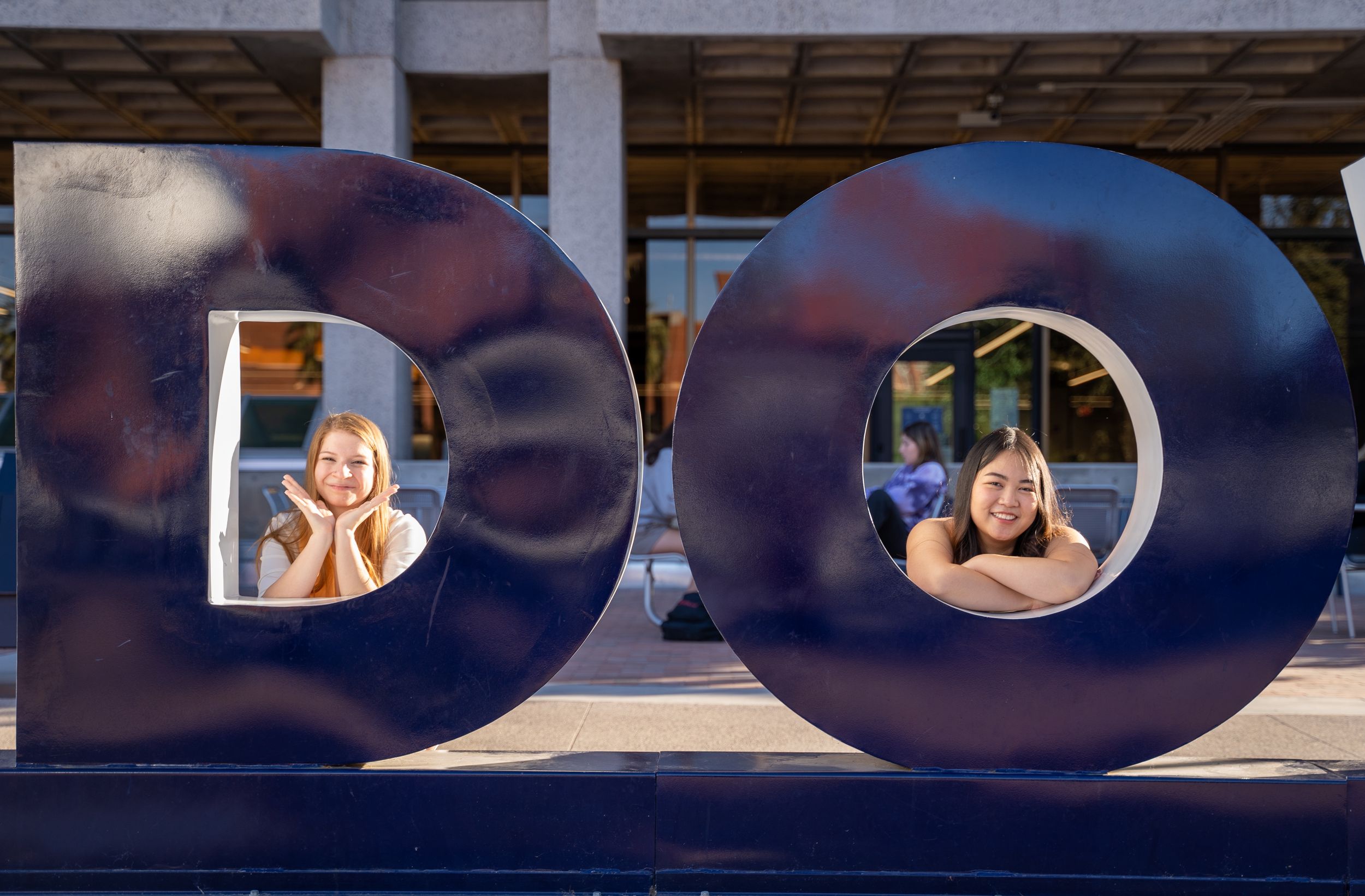 Senior portrait of two grads inside the "DO" of the Bear Down sign at the University of Arizona, captured by N&D Media.