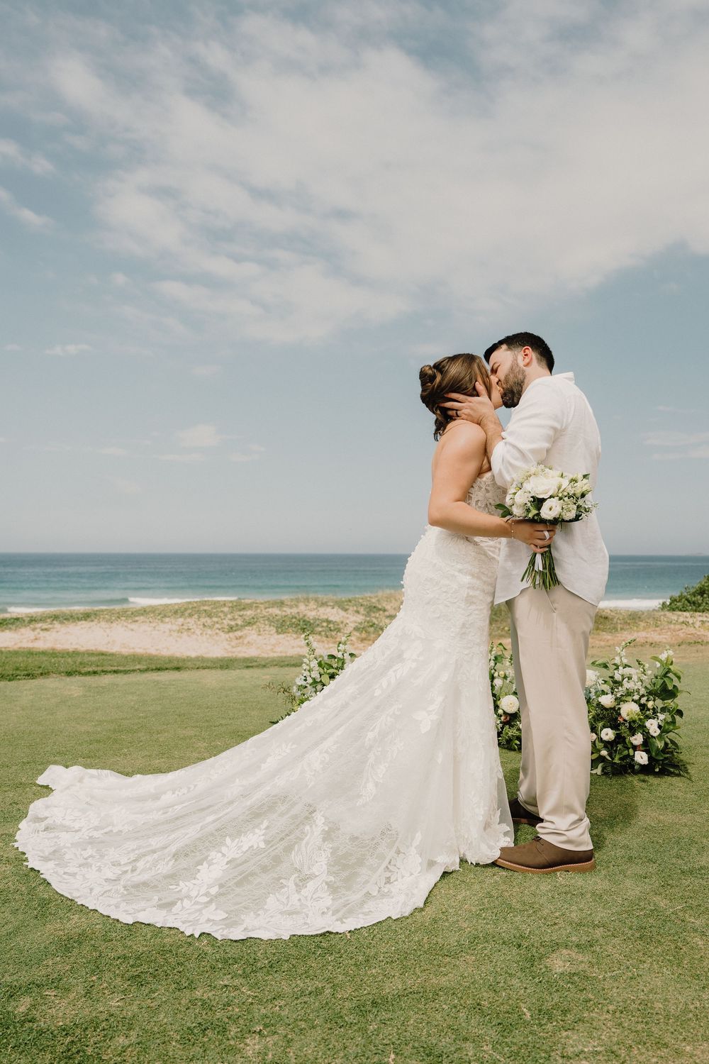 A romantic beach wedding sequence shows a couple in white embracing on a grassy oceanside cliff with flowing bridal gown details.
