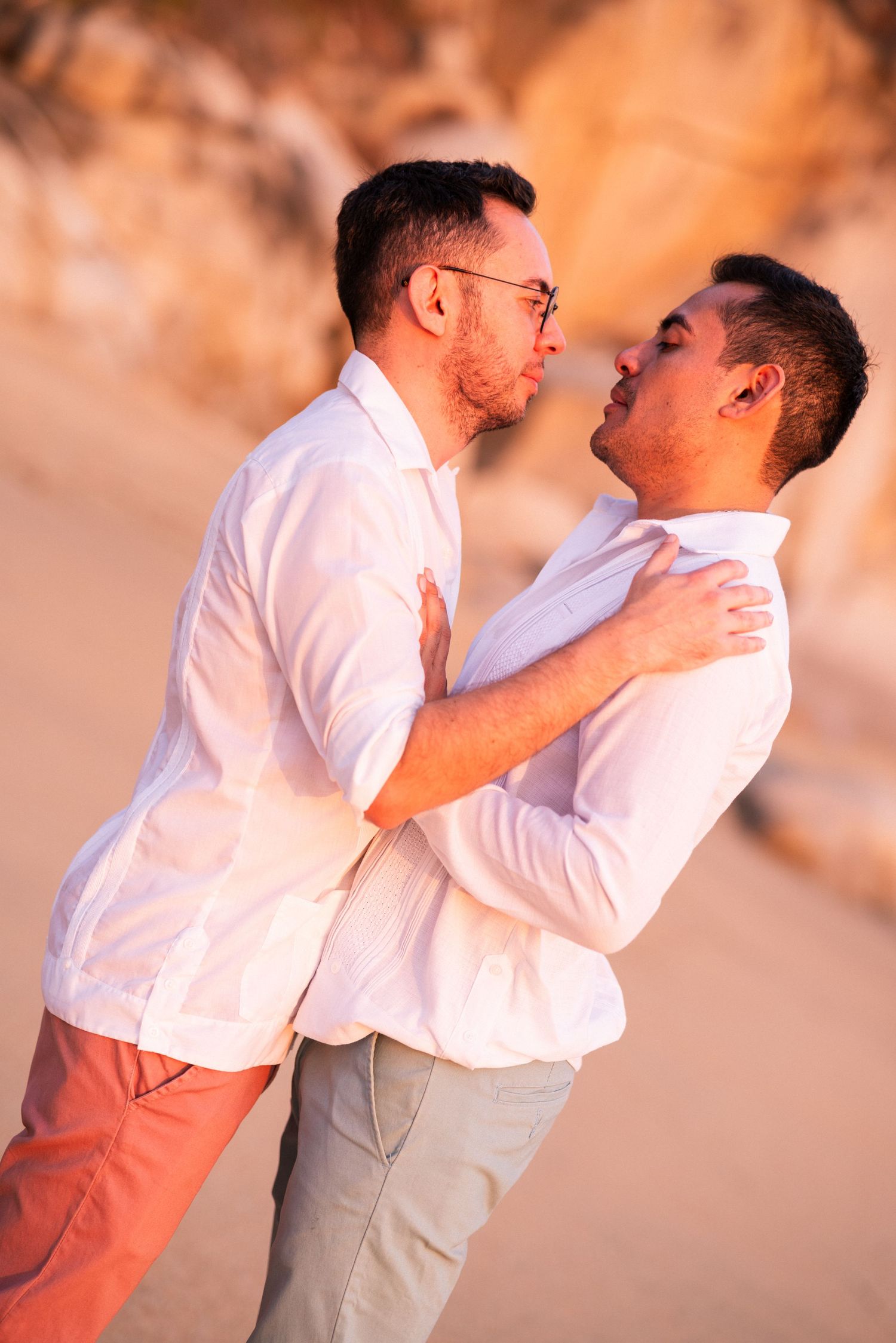 Two people in white shirts embrace lovingly during a romantic sunset photoshoot.