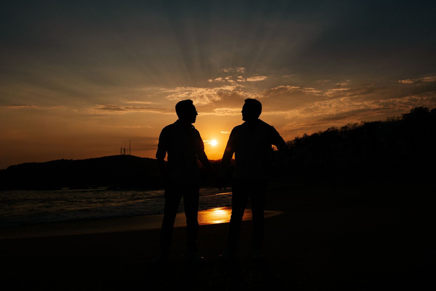Silhouettes of elephants walking along horizon against dramatic orange sunset sky in Africa.