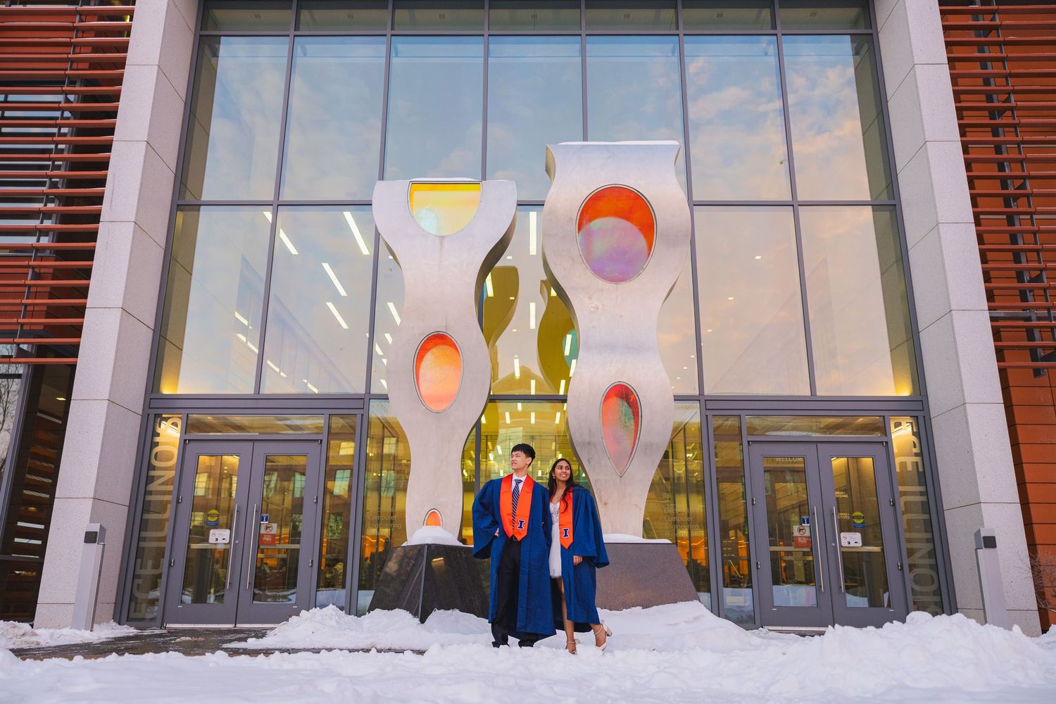 Cute graduating couple posing beside each other in front of the ECE building at UIUC