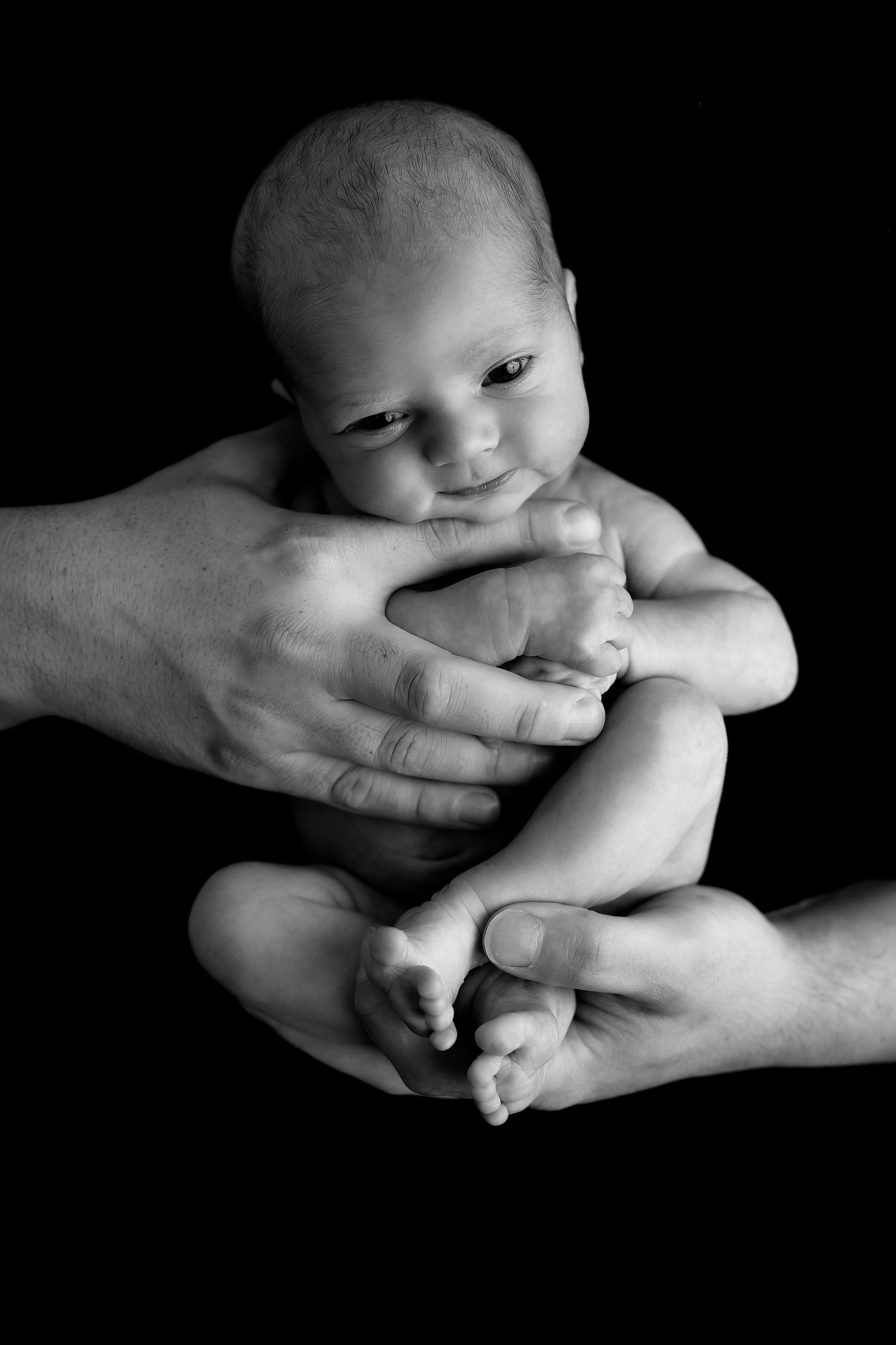 Black and white artistic newborn photography series showing tiny feet and hands held gently.