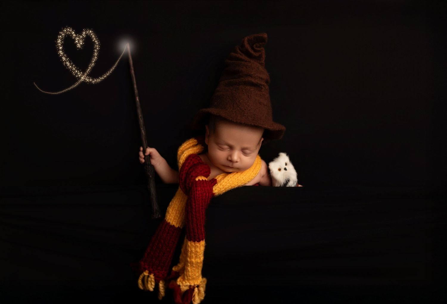 A person in black clothing holds a yellow and red striped scarf against a dark background.
