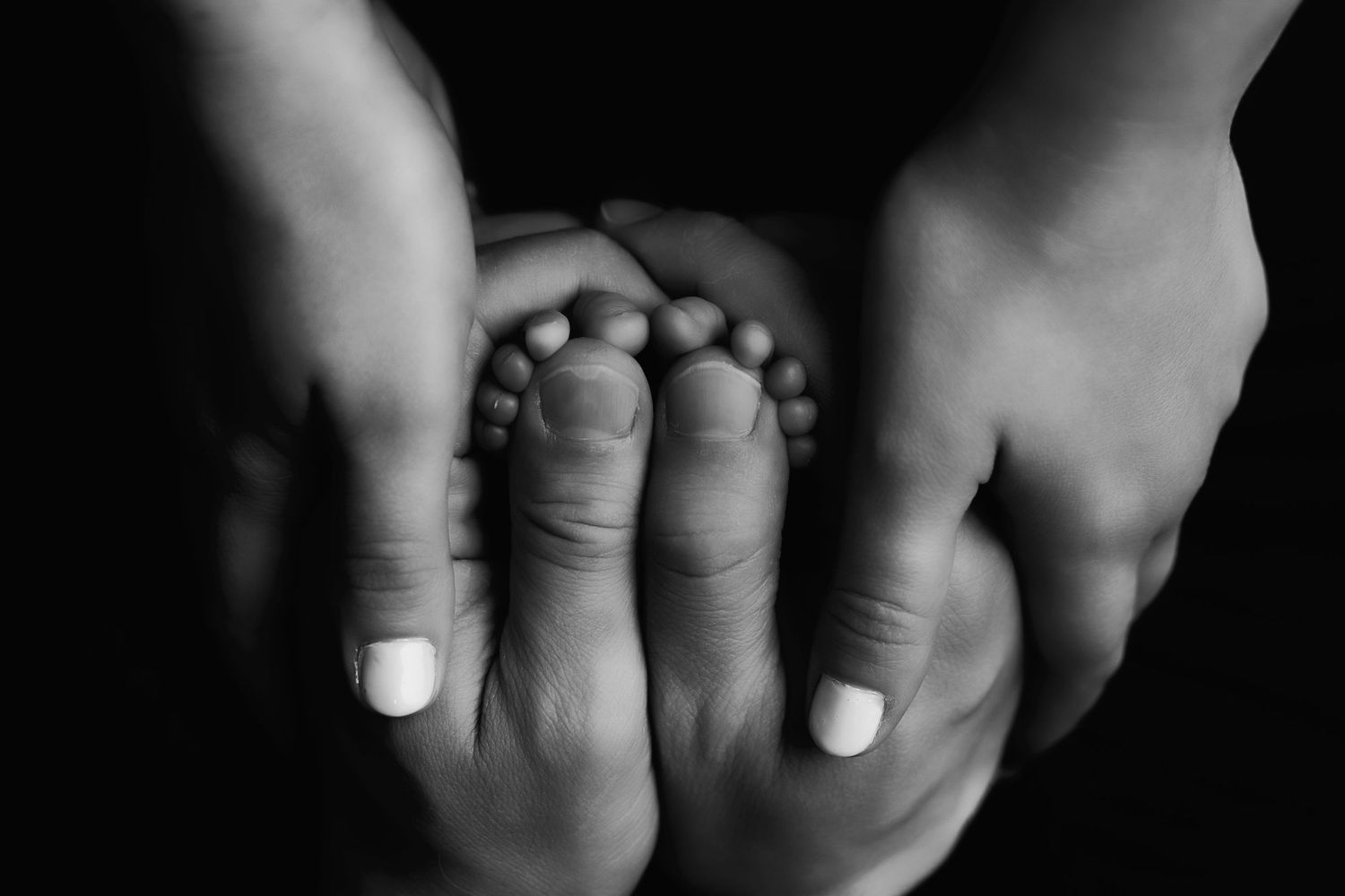 Black and white close-up photograph of hands with wedding rings in various poses against a dark background.