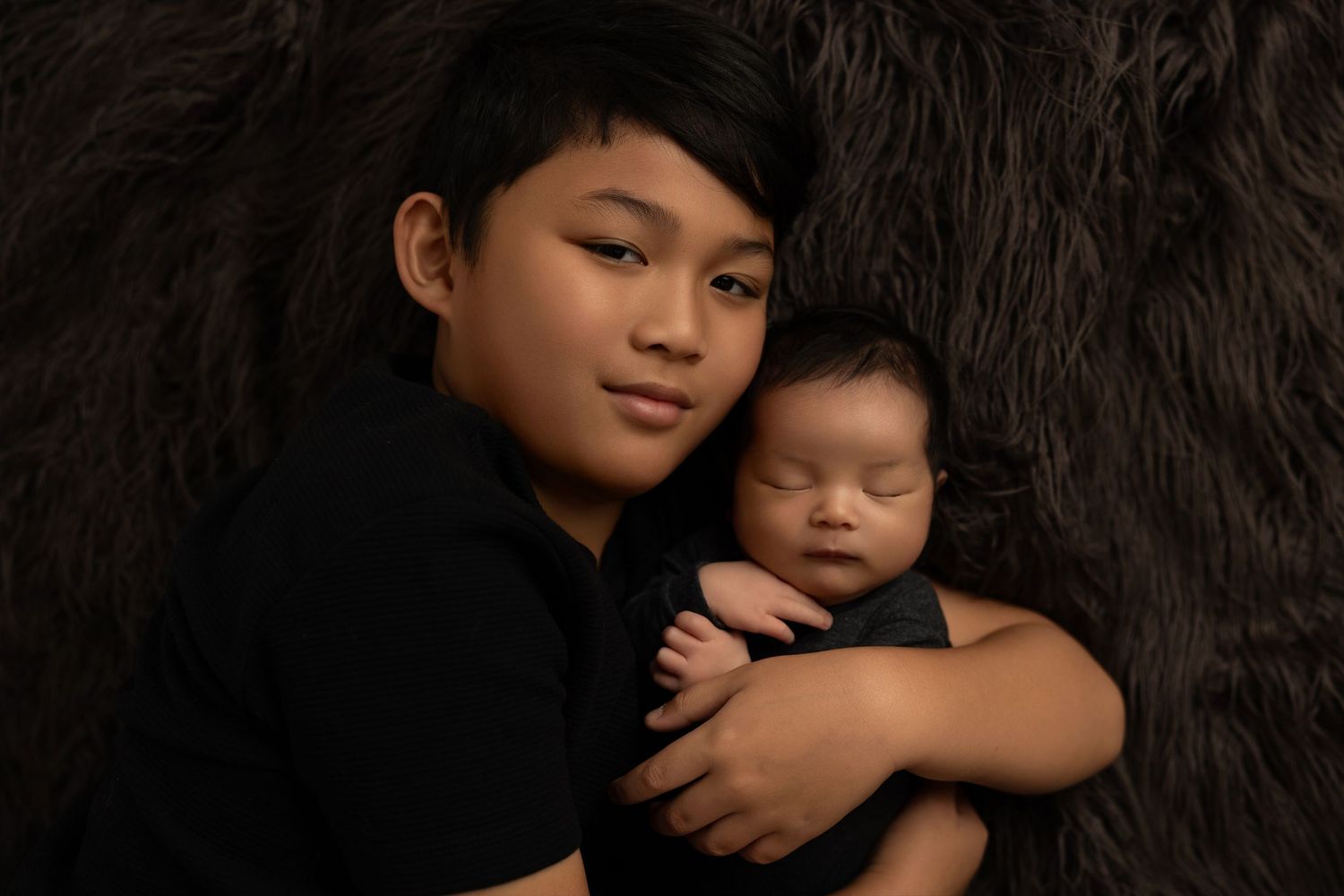 Professional black and white studio portrait series showing tender embraces against dark background.