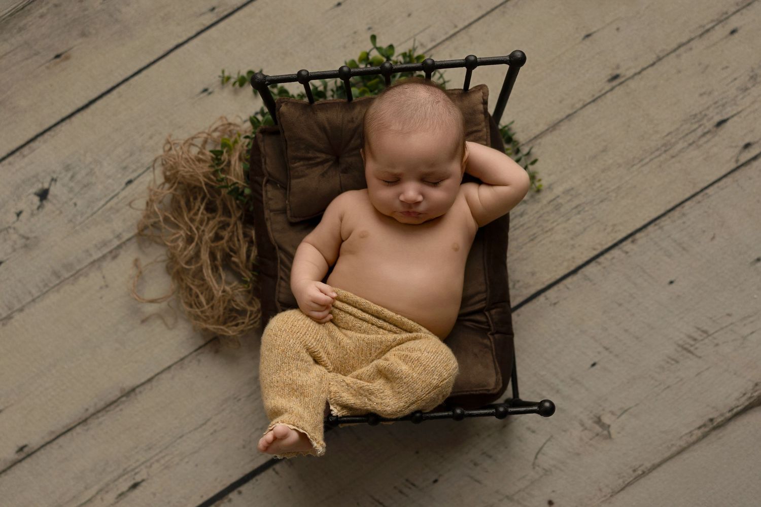 A series of black and white photos show a baby lying on wooden floorboards in different playful poses.