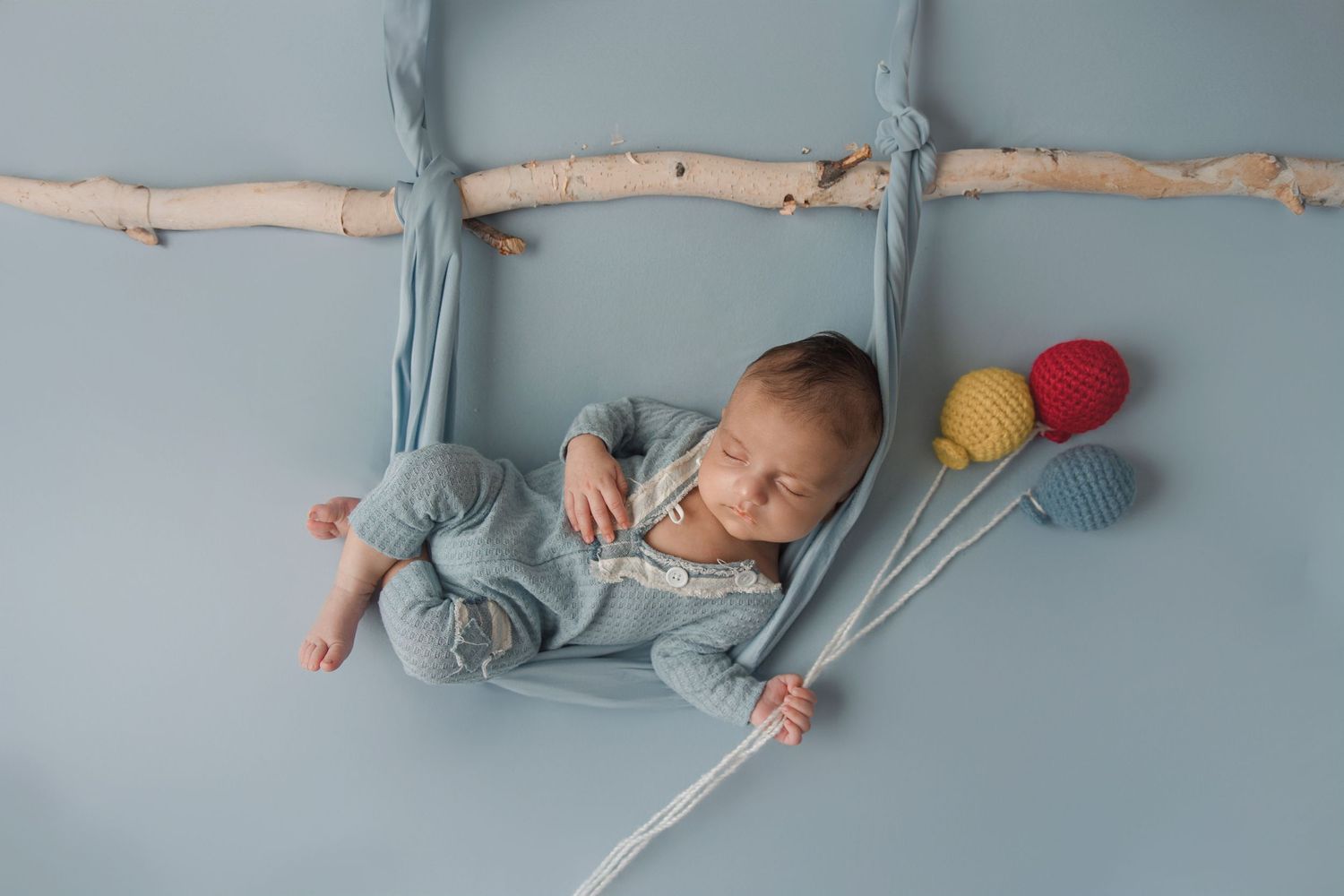 A baby sleeping peacefully in a light blue outfit against a matching blue background.