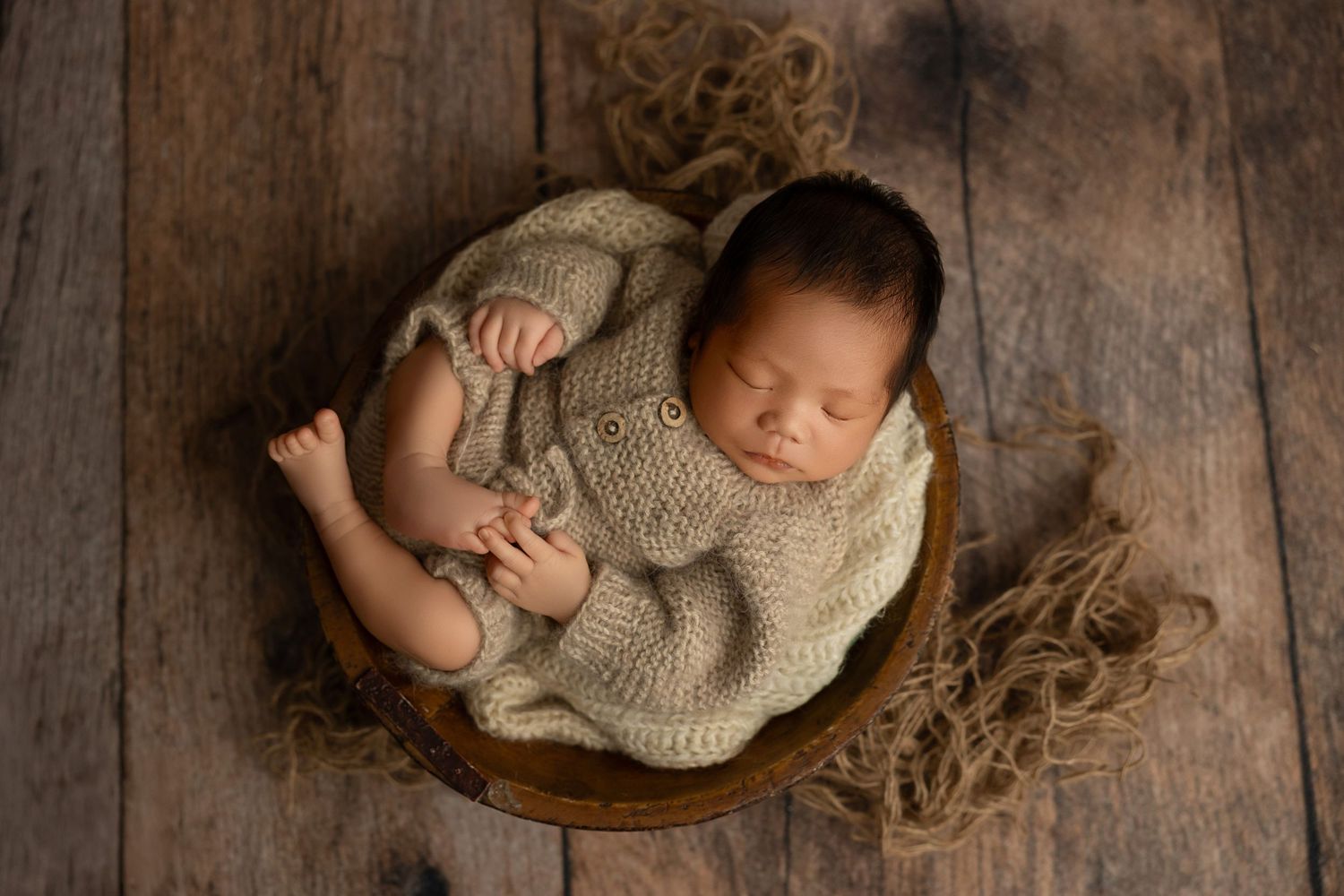 Newborn photography session featuring peaceful sleeping baby on rustic wooden backdrop.