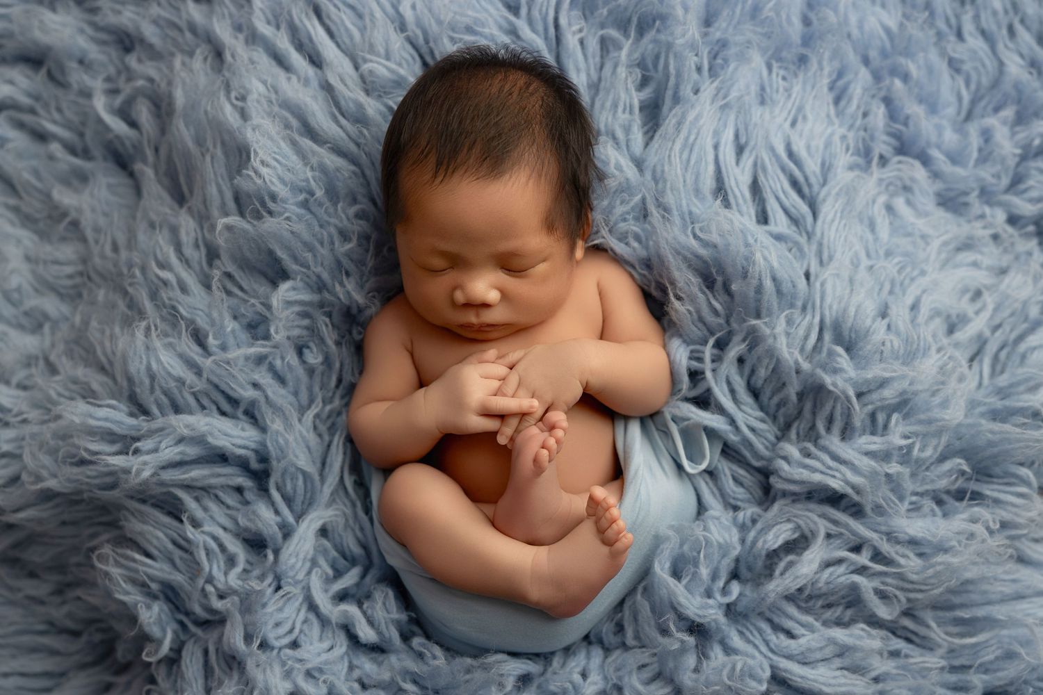 A series of newborn baby photos on soft blue fur fabric showing different sleeping poses and positions.