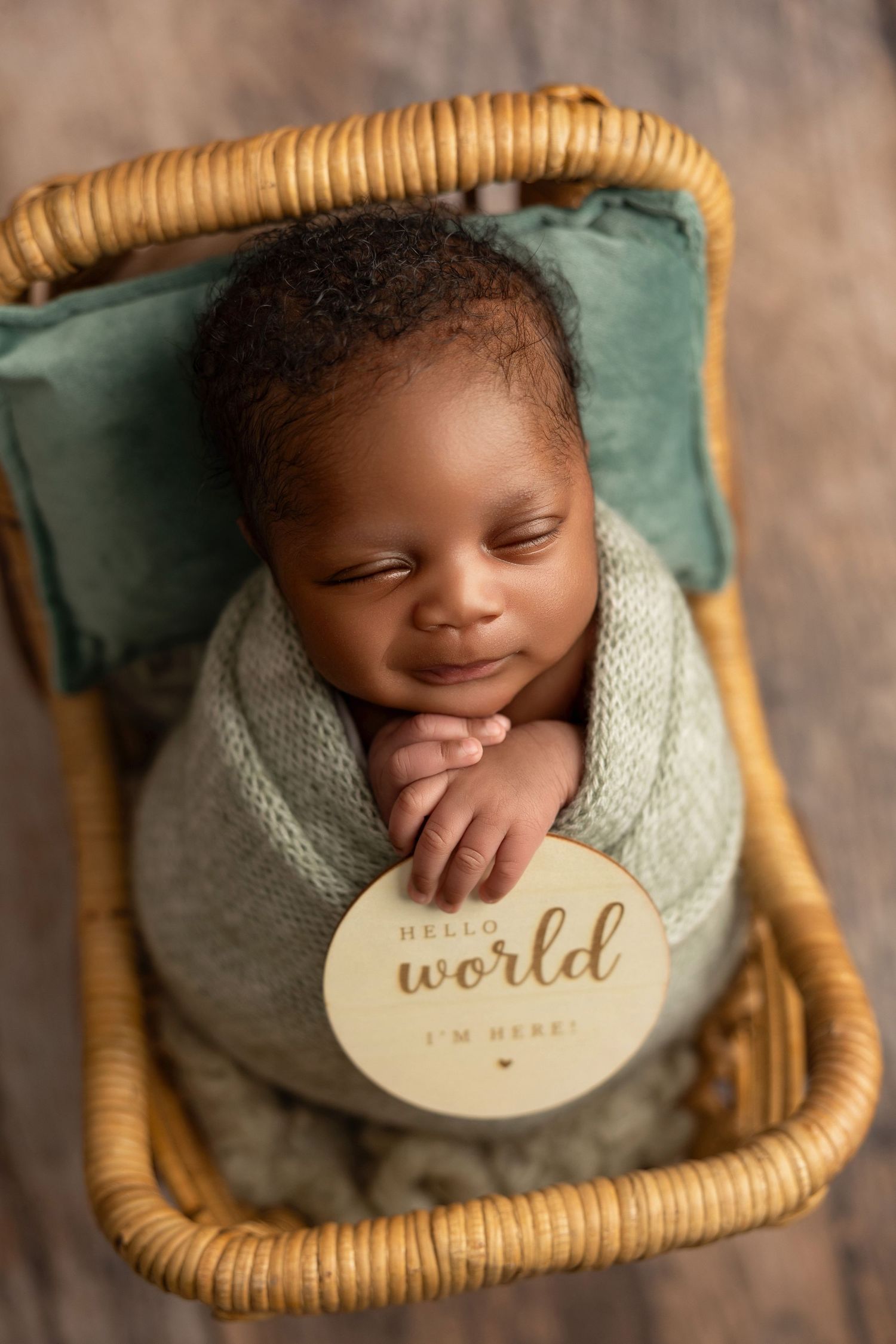 A series of overhead shots showing a newborn in a woven basket with a wooden 'Hello World' sign.