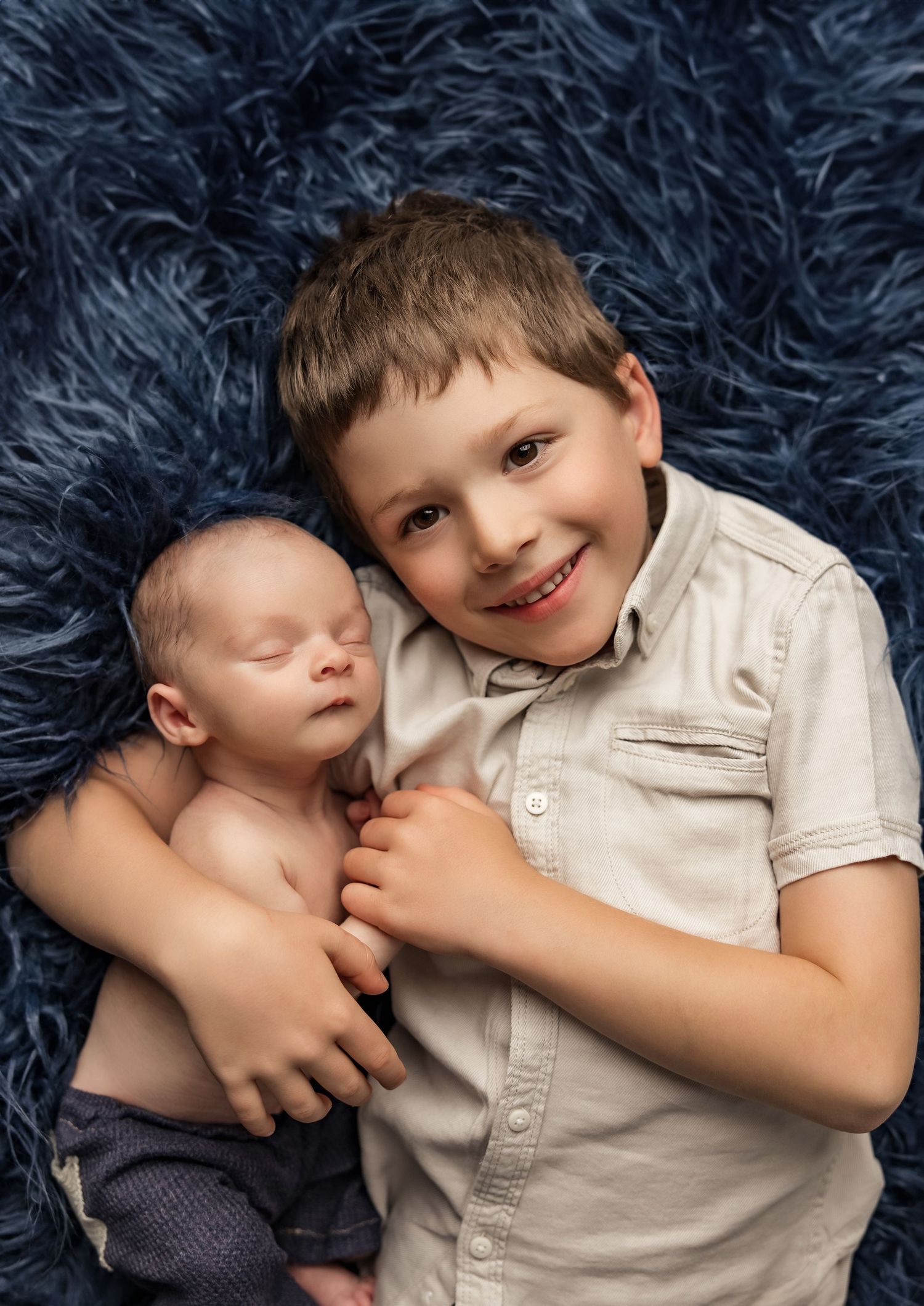 Two young children share a tender moment on a dark blue textured background in a series of candid shots.