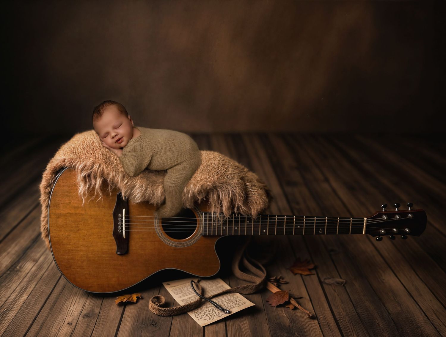 A rustic wooden acoustic guitar lies on a dark wooden floor with warm lighting and vintage aesthetic.