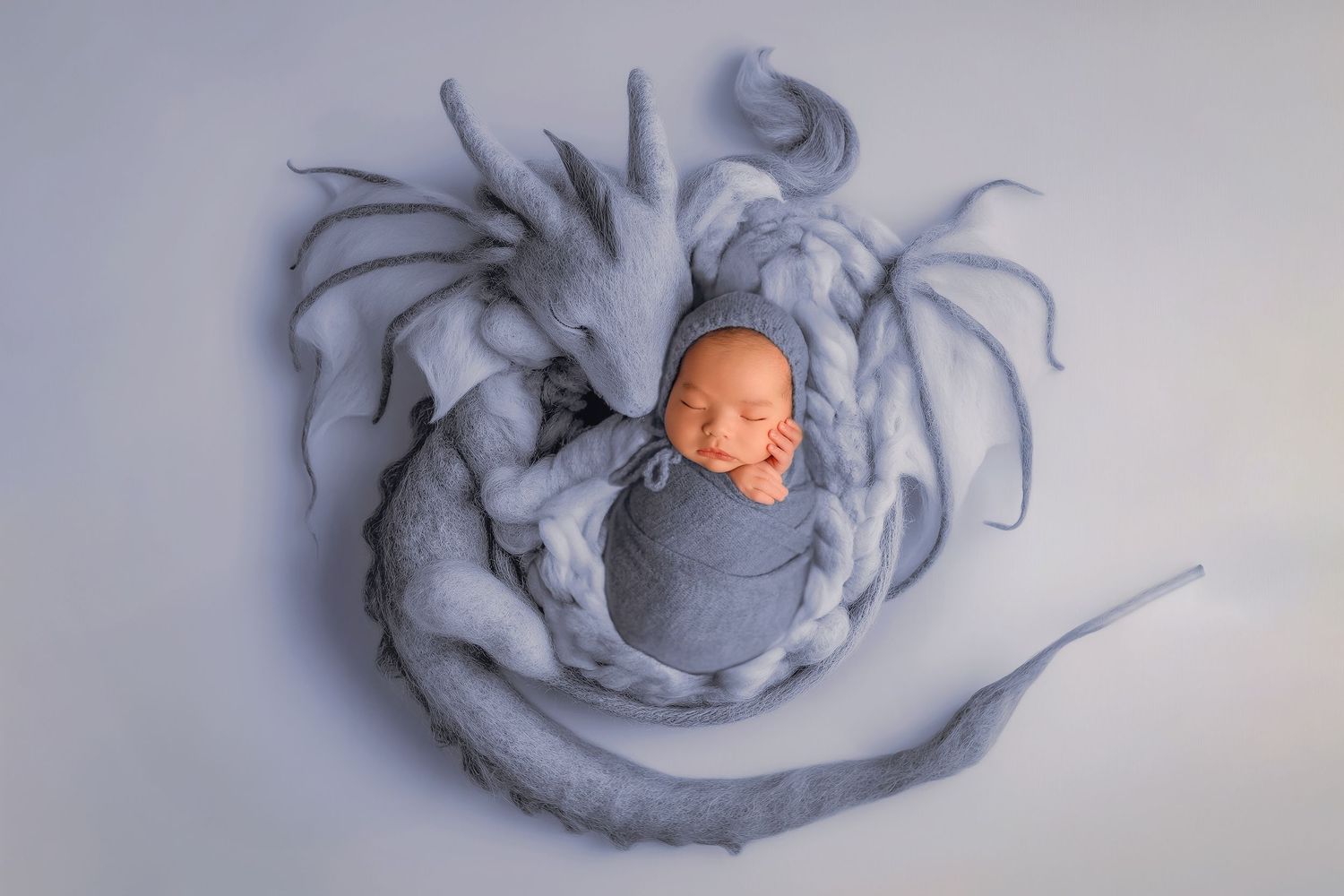 A series of seven ceramic sculptures showing the progressive stages of a sleeping figure curled up in flowing fabric.