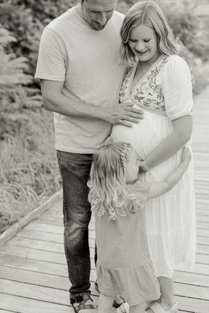 Romantic black and white photos of a couple embracing on a wooden boardwalk surrounded by nature.