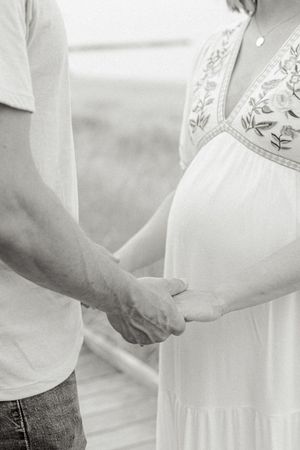 Close-up black and white images showing gentle hands holding a baby's feet in sequence.