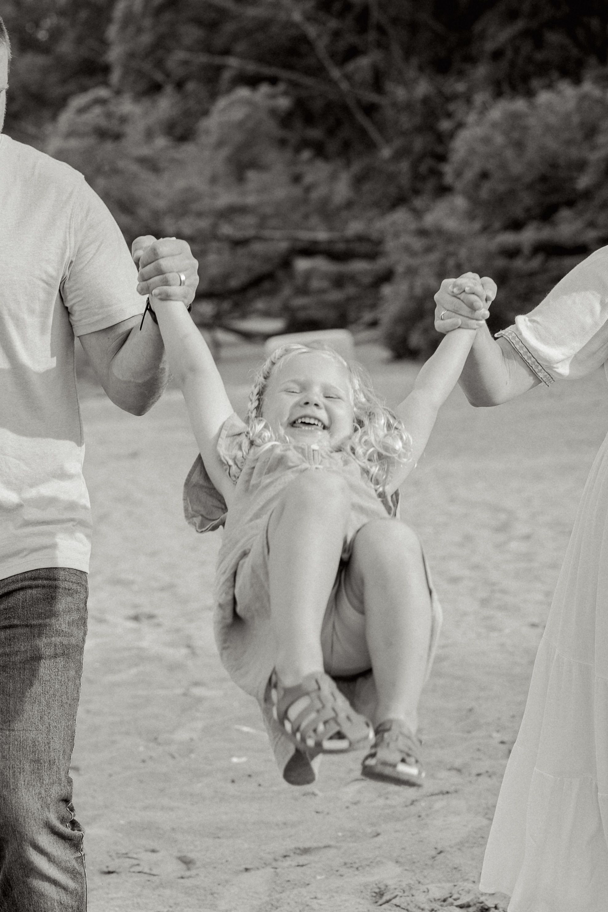 A series of black and white photos showing someone swinging and playing joyfully at the beach.