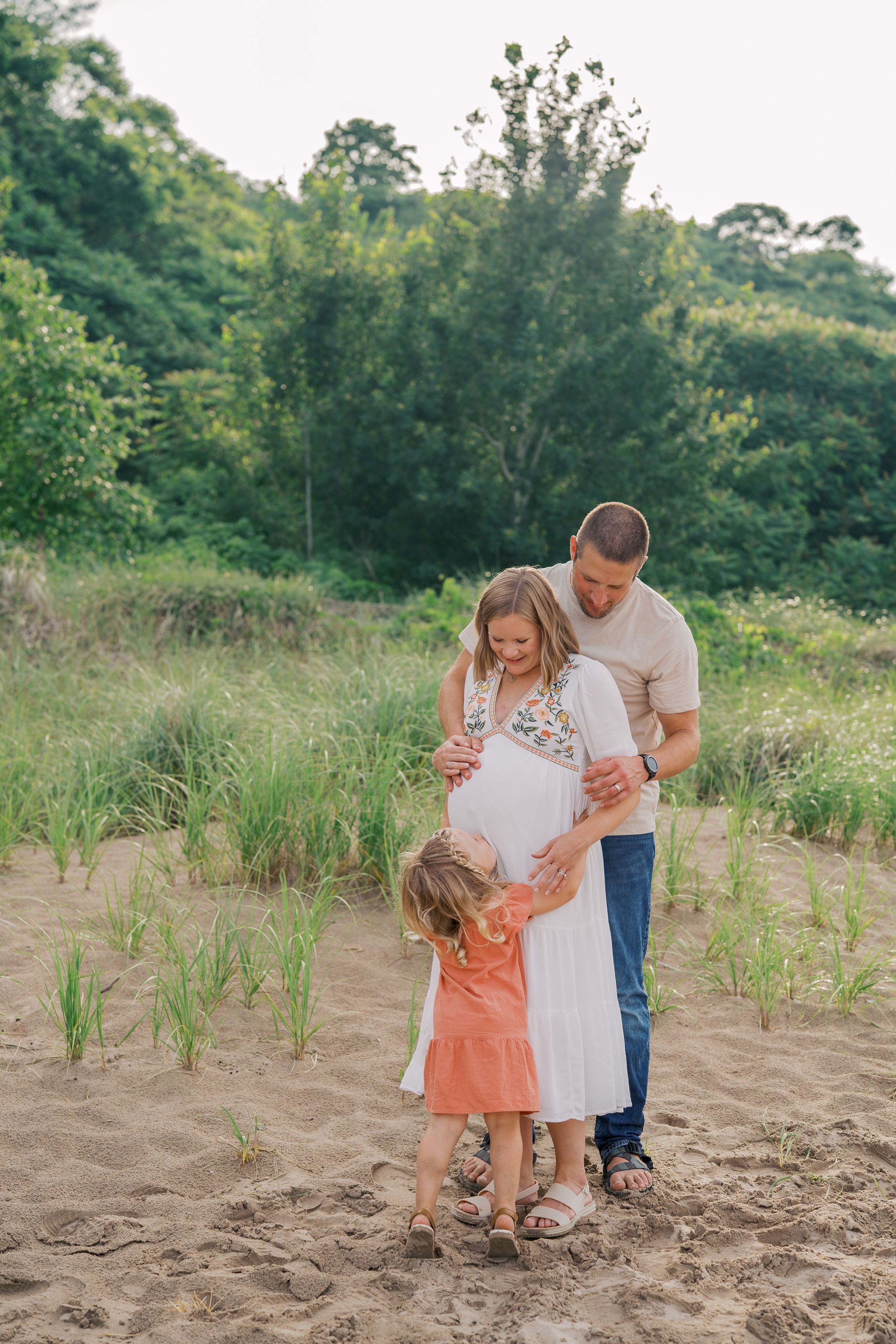 A family shares a special moment together in a grassy field during a photo session.