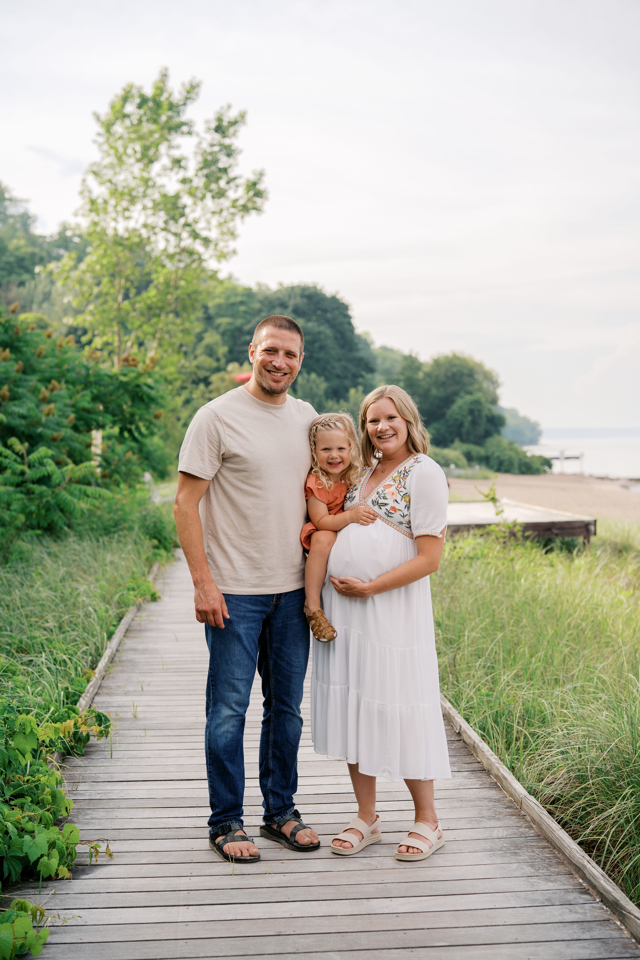 Family enjoying a summer day together on a wooden boardwalk path near the beach.
