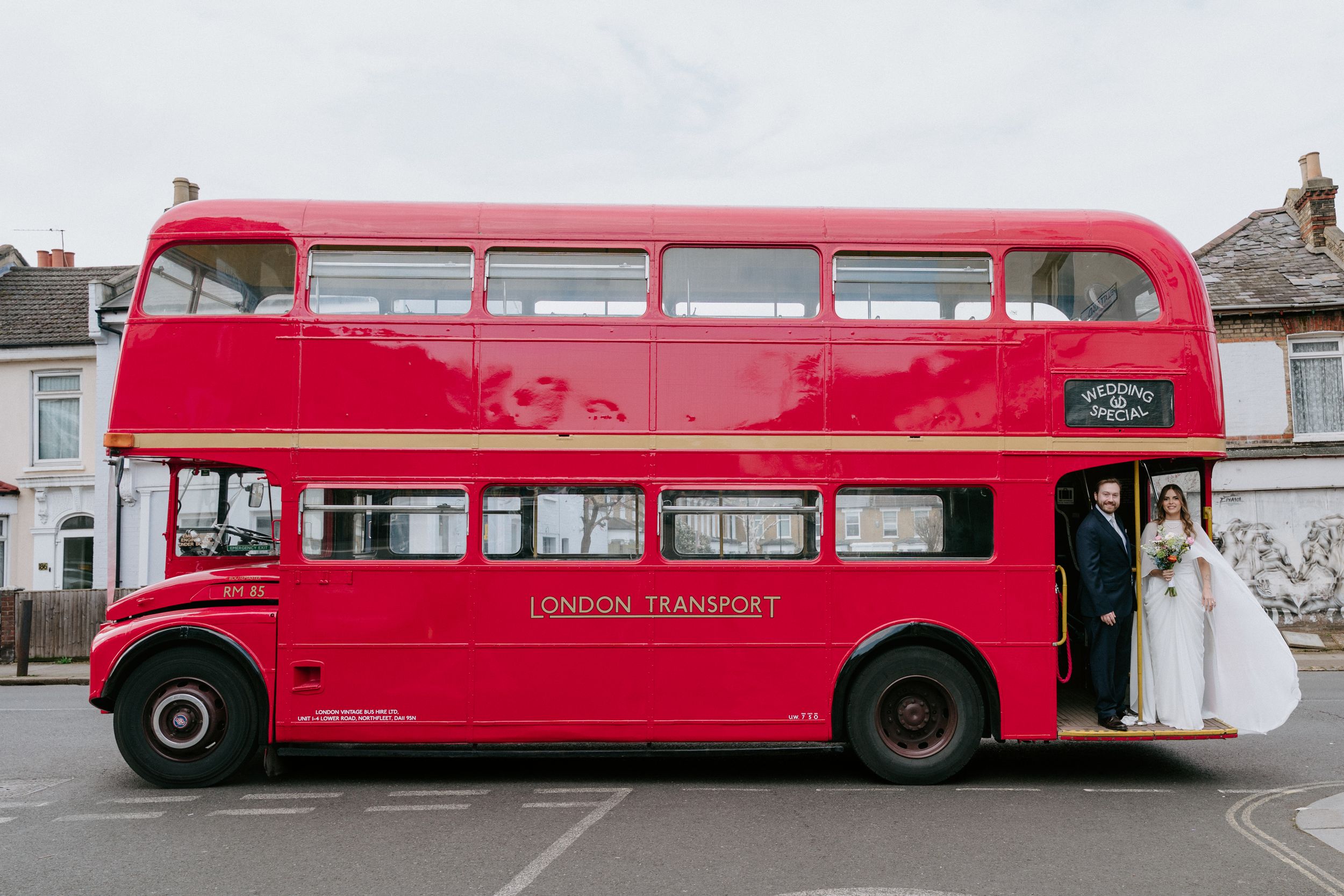 A series of red vintage double decker buses parked in a line showing their elongated profiles.