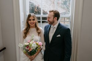 A bride and groom share tender moments together in an elegant indoor setting with natural light streaming through windows.