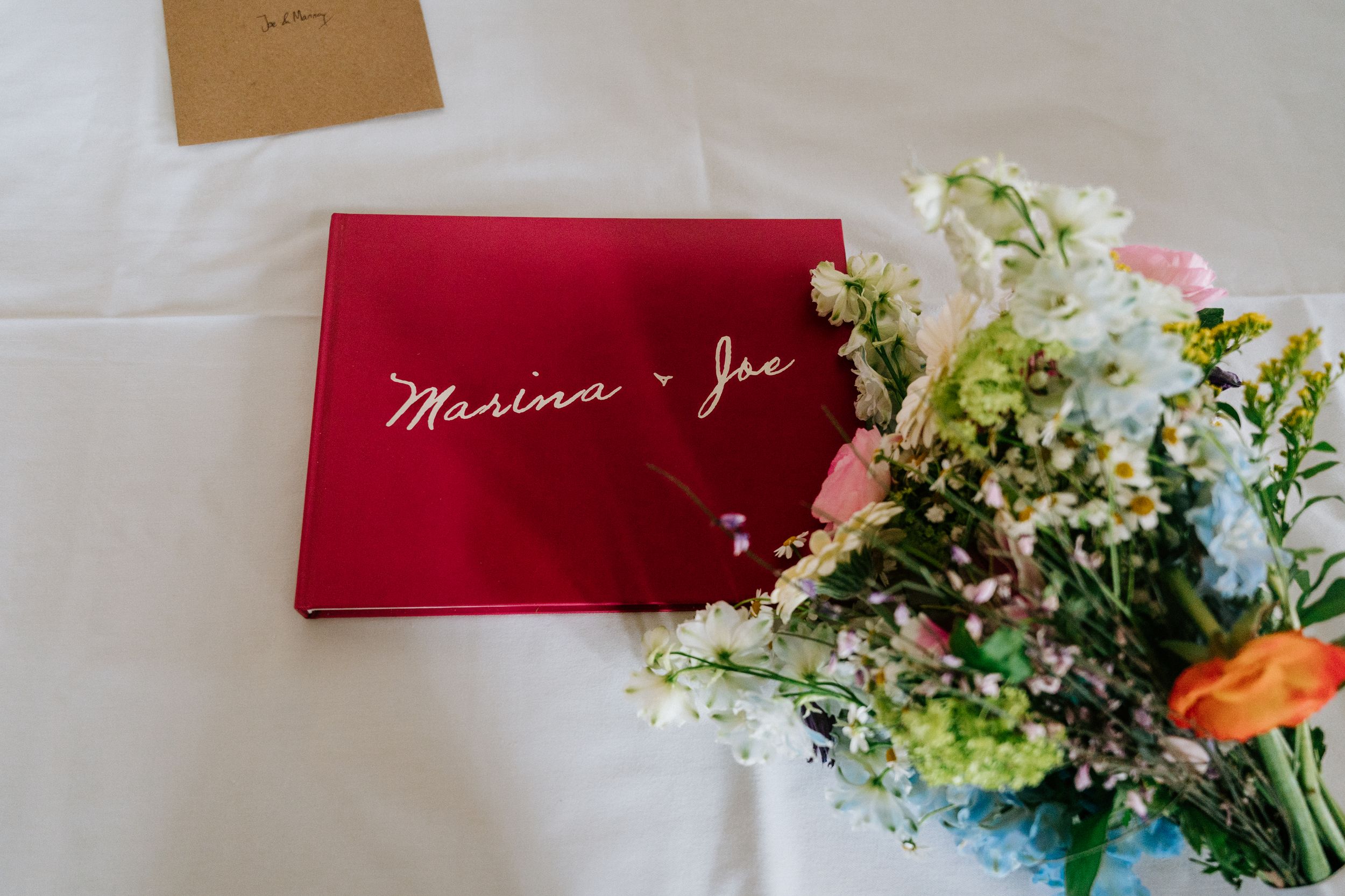 Colorful floral arrangements with pink and white name cards displayed on a light gray surface for a wedding event.