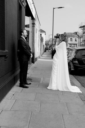 A sequence of black and white photos showing a ghost-like figure in a white sheet following a person down an urban sidewalk.