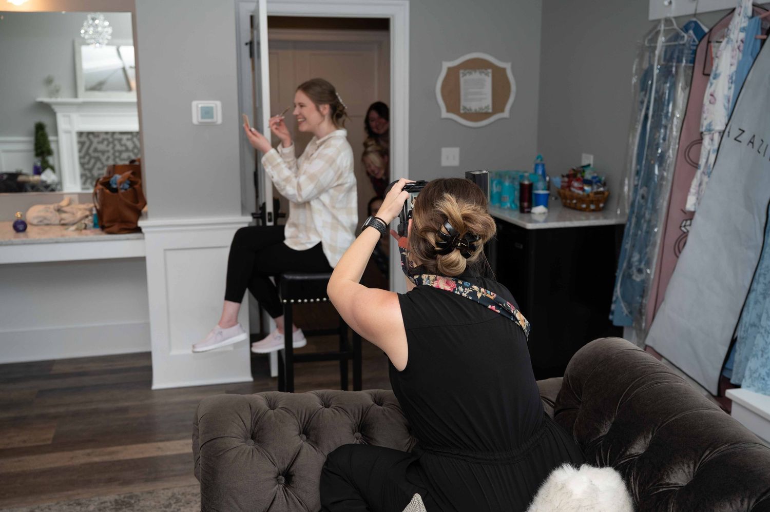 Professional photographer takes photos in a modern home interior with gray walls and hardwood floors.