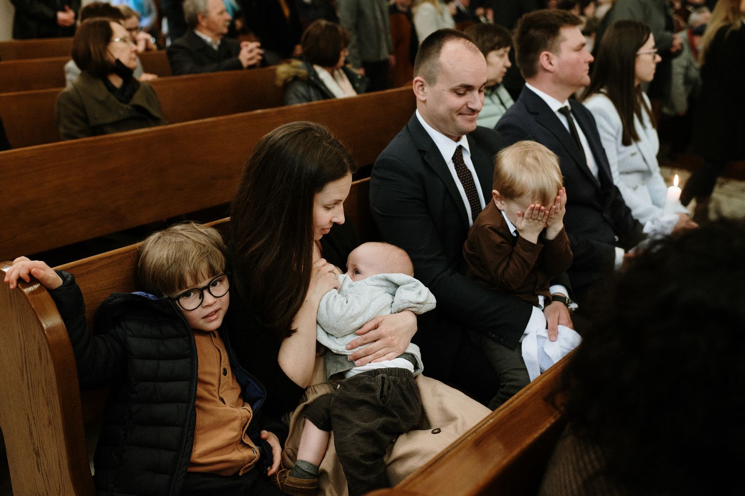 People sit in wooden church pews during what appears to be a formal ceremony or service.