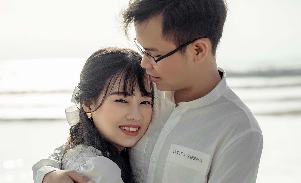 Intimate beach portrait capturing a tender moment in soft lighting.