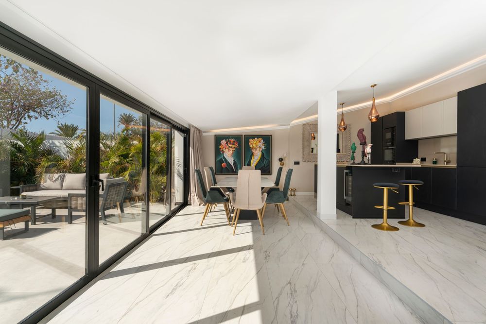 Modern minimalist interior with white walls and floor-to-ceiling windows creating a bright, open living space.