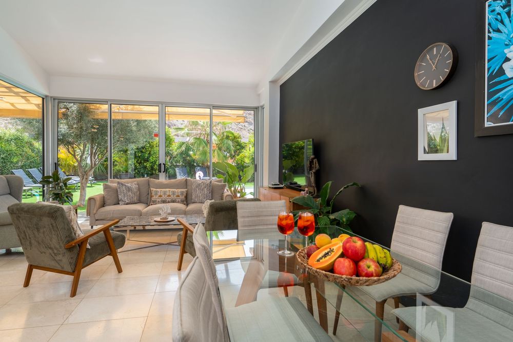 Modern open concept living room with dark accent wall, large windows, and contemporary furnishings in a luxury home.