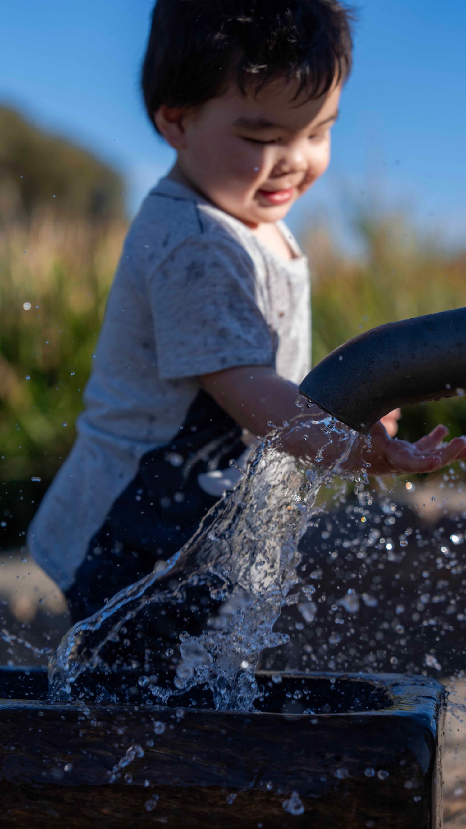 Child playing with splashing water outdoors on a sunny day. In melbourne