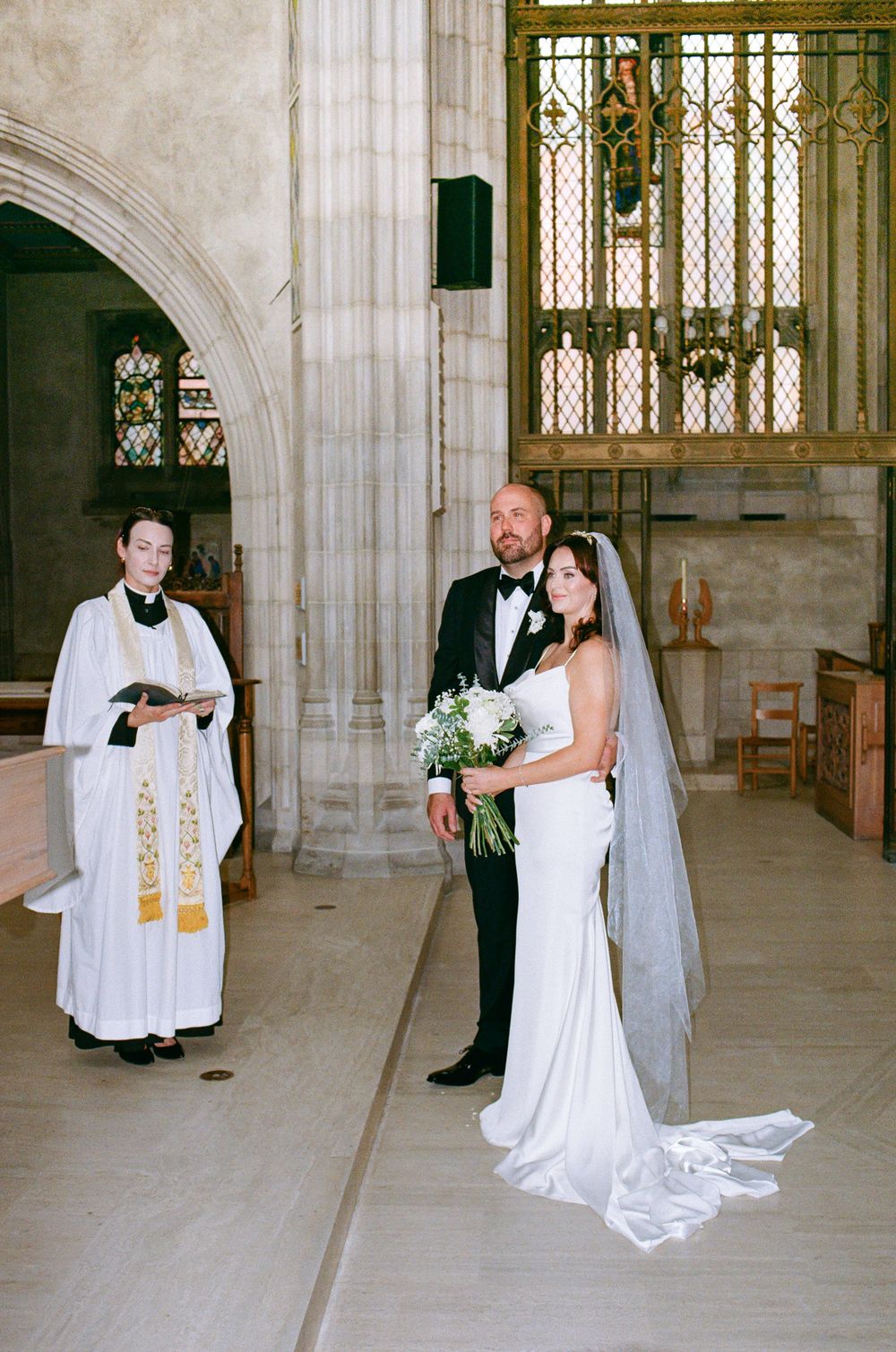 Bride and groom stand at the altar during a church wedding ceremony with an officiant.