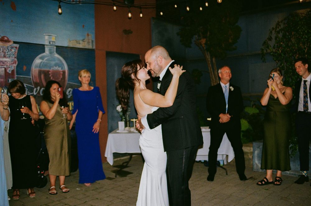 Newlyweds share their first dance while guests clap and celebrate at the reception.
